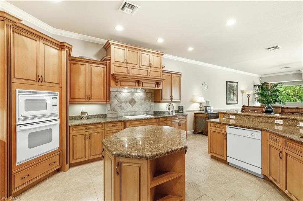 Kitchen featuring a built-in oven and microwave combination, an island with countertop seating, recessed lighting, and a tile backsplash