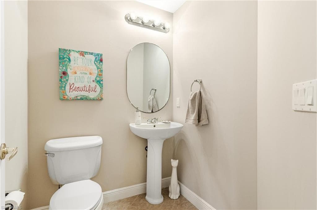 Half Bathroom on first floor with Pedestal sink with an oval mirror and a five-bulb vanity light fixture