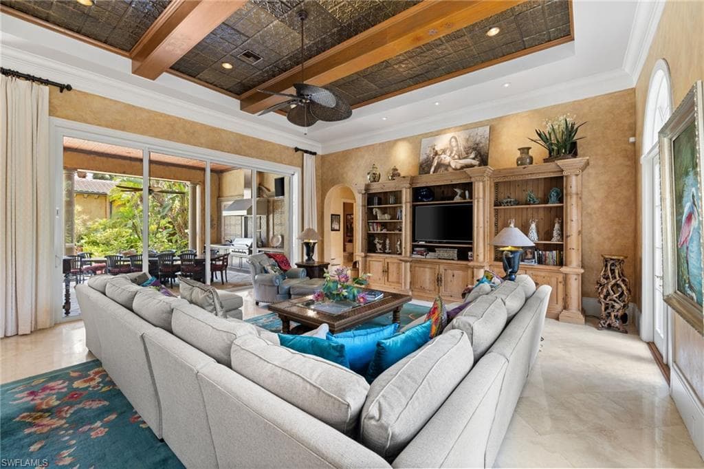 Spacious living area featuring large format tile flooring and an ornate pressed tin ceiling with exposed wood beams