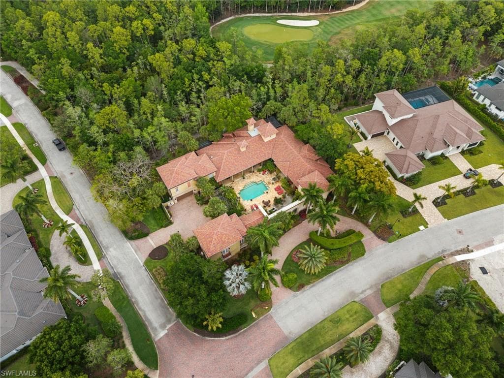Mediterranean-style property featuring a central courtyard with a swimming pool, a red tile roof, and a meticulously landscaped circular driveway
