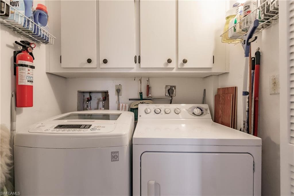 laundry in residence with storage cabinets.