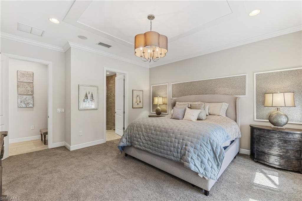 Carpeted bedroom featuring a tray ceiling with a chandelier and recessed lighting