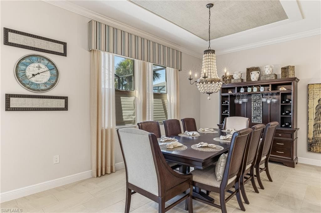 Formal dining space featuring a coffered ceiling with a chandelier, large windows with valance and drapes, and a built-in dark wood hutch