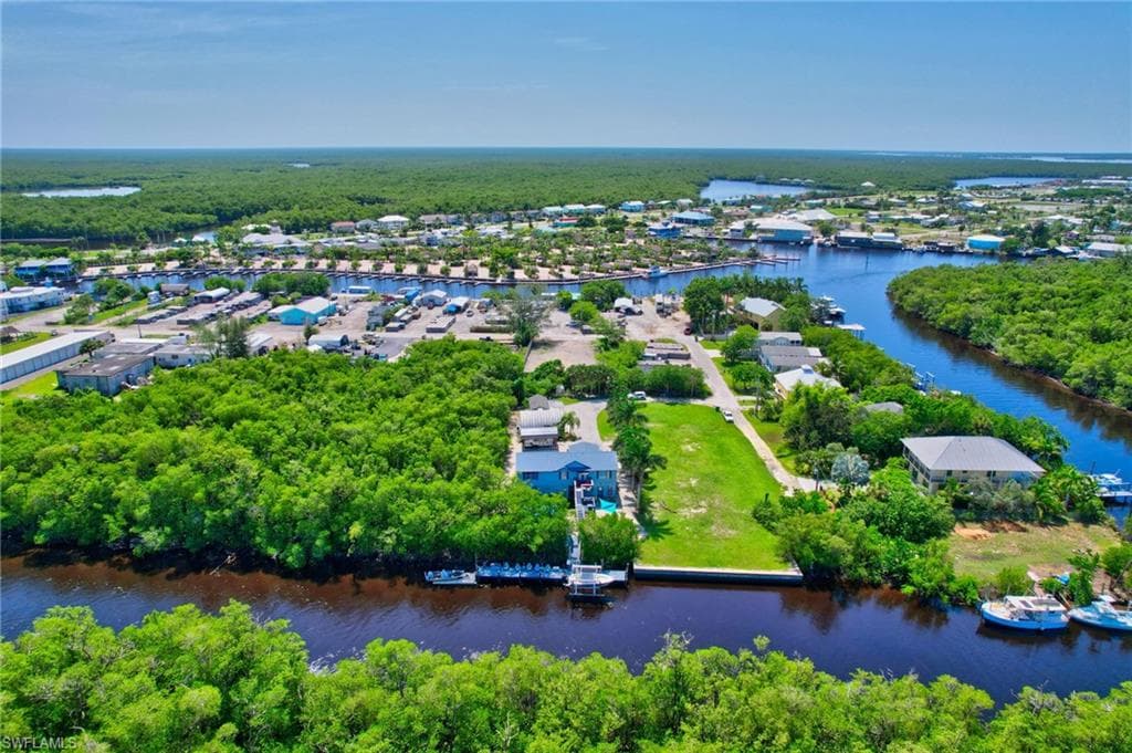 Waterfront property featuring a private boat dock, lush green landscaping, and direct access to a navigable waterway