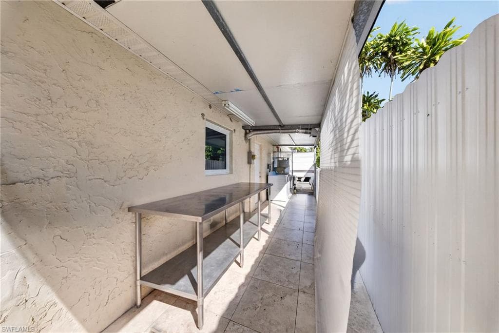 Exterior pathway featuring a textured stucco wall, tile flooring, and a stainless steel work surface