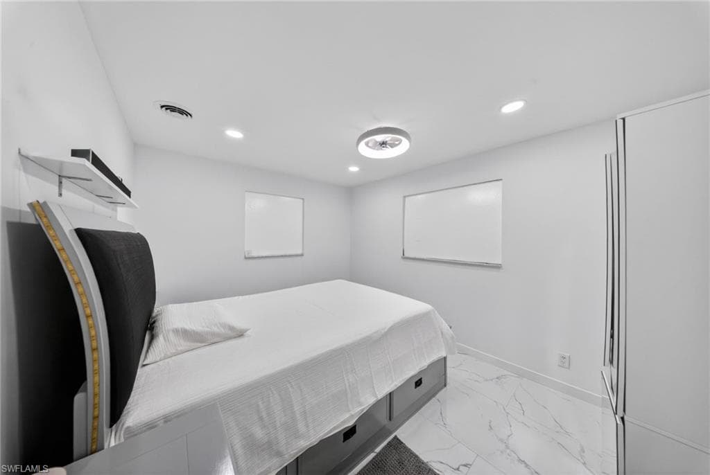 Room featuring white walls, recessed ceiling lighting, a modern flush-mount ceiling fixture, and white marble-look flooring