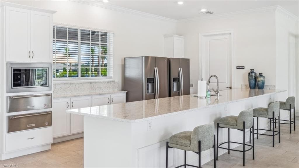 The kitchen features white cabinetry, stainless steel appliances, and light-colored countertops