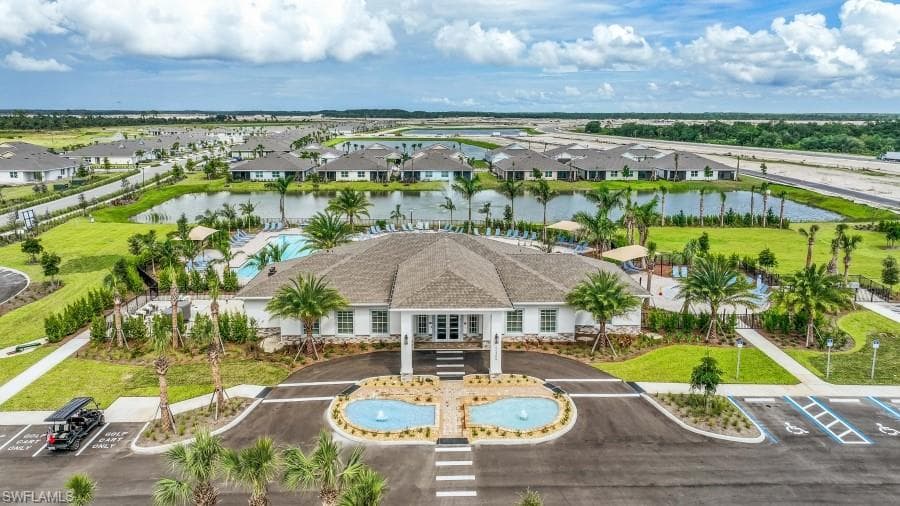 The property features a prominent clubhouse building with a paved entrance and two decorative fountains, surrounded by lush landscaping and palm trees