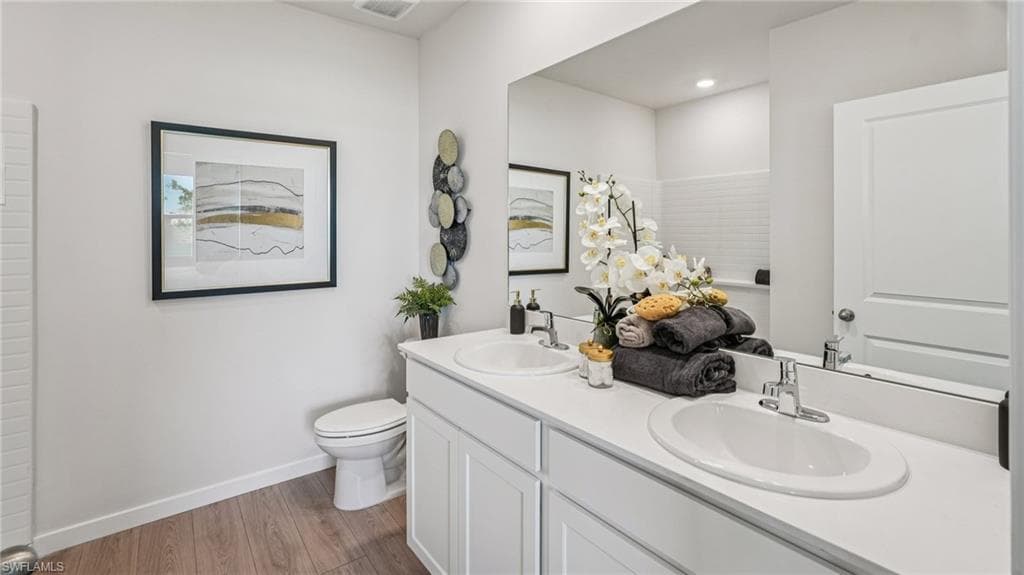 Bathroom featuring a dual vanity with white cabinetry, integrated sinks, and chrome faucets