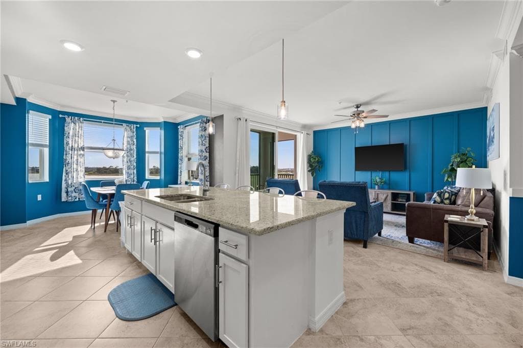 Open-concept living space featuring a central kitchen island with granite countertops, stainless steel appliances, and white cabinetry