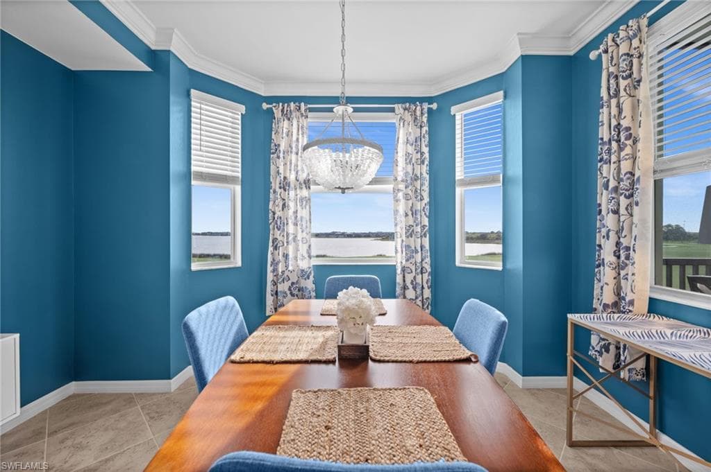 Bay window dining area featuring a crystal chandelier, crown molding, and tile flooring
