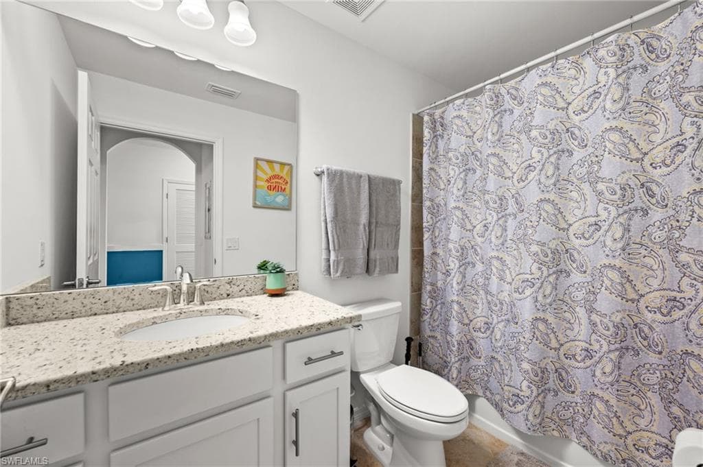 Bathroom featuring a single vanity with a light-colored speckled countertop, an undermount sink, and a chrome faucet