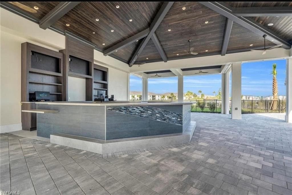 Expansive outdoor living space with a vaulted wood-finish ceiling, exposed beams, and recessed lighting
