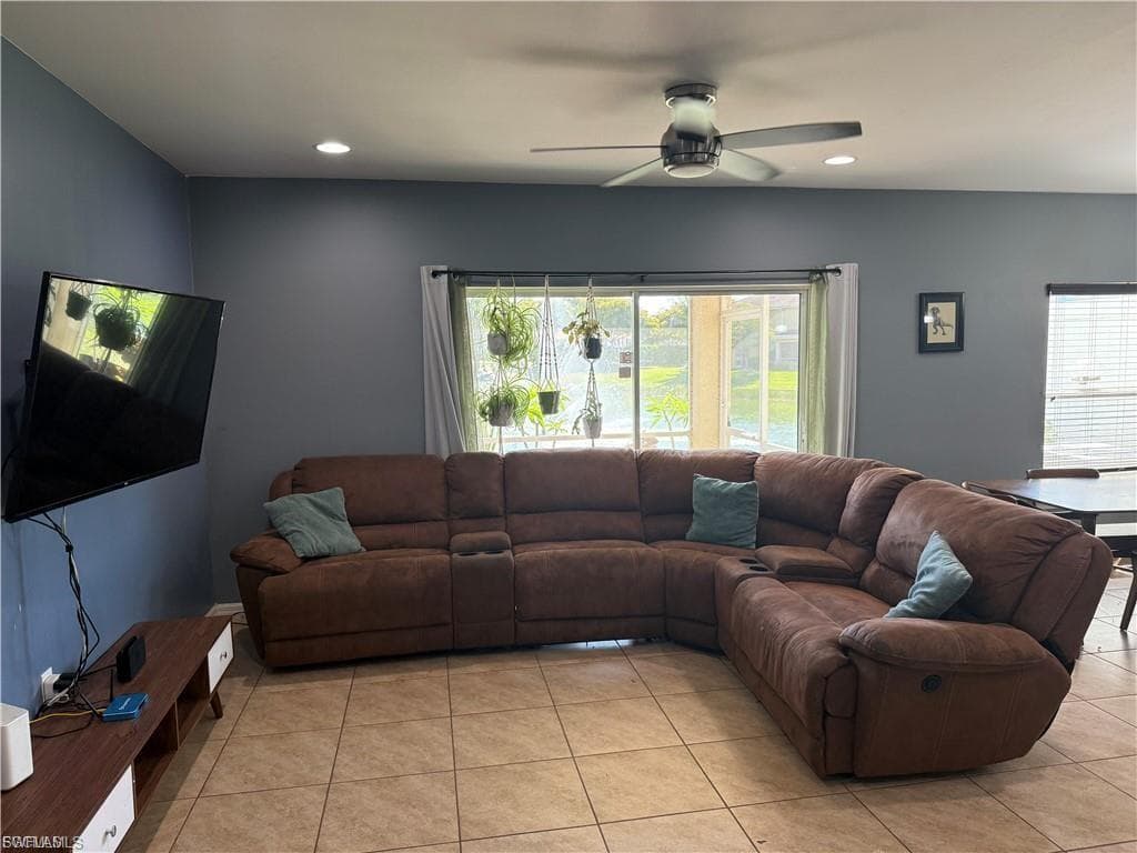 Spacious living area featuring tile flooring, a ceiling fan with integrated lighting, recessed lighting, and large sliding glass doors providing access to the outdoors