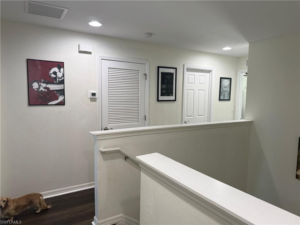 Second-story hallway featuring dark wood-finish flooring, white walls, recessed lighting, and white baseboards