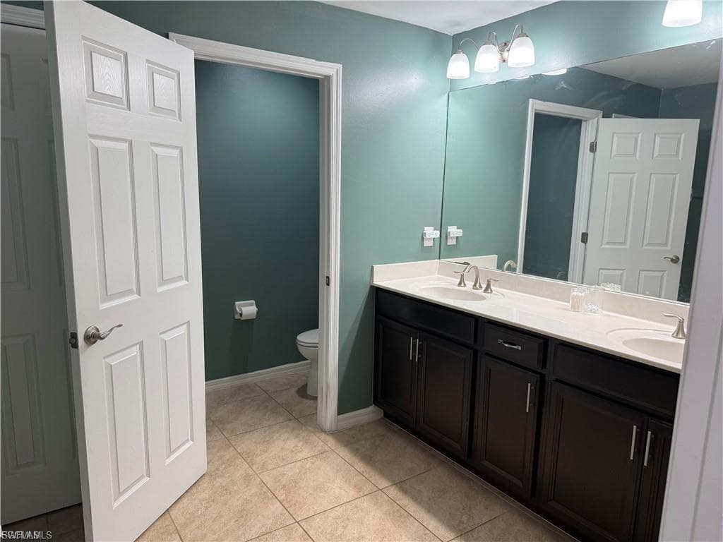 Bathroom featuring a dual vanity with dark wood cabinetry, white countertops, and undermount sinks