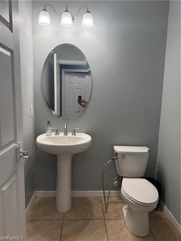 Pedestal sink with a brushed nickel faucet, an oval mirror, and a three-light vanity fixture