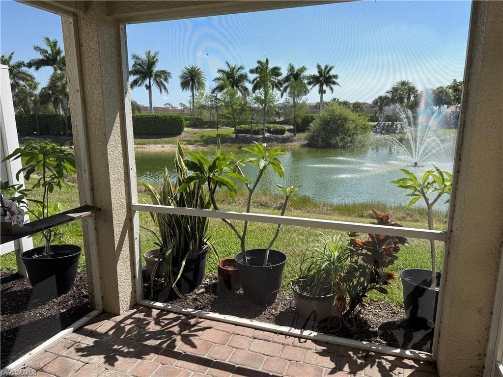 Screened patio featuring brick paver flooring overlooking a lake with multiple fountains