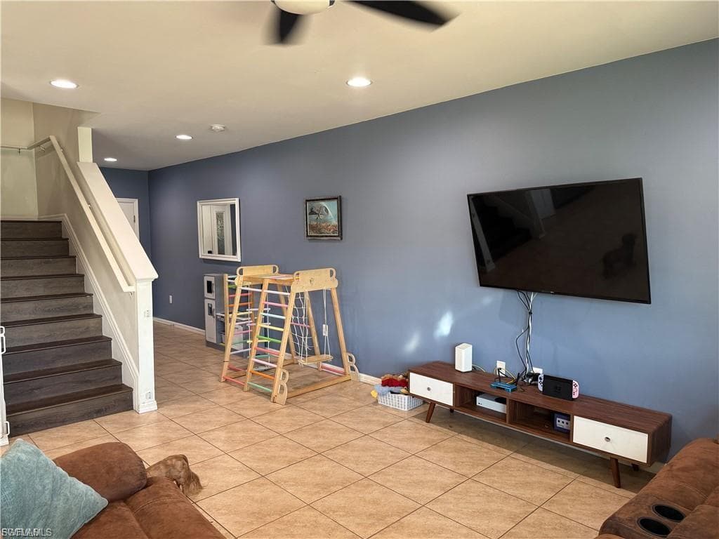 Living area featuring tile flooring and a ceiling fan with integrated lighting