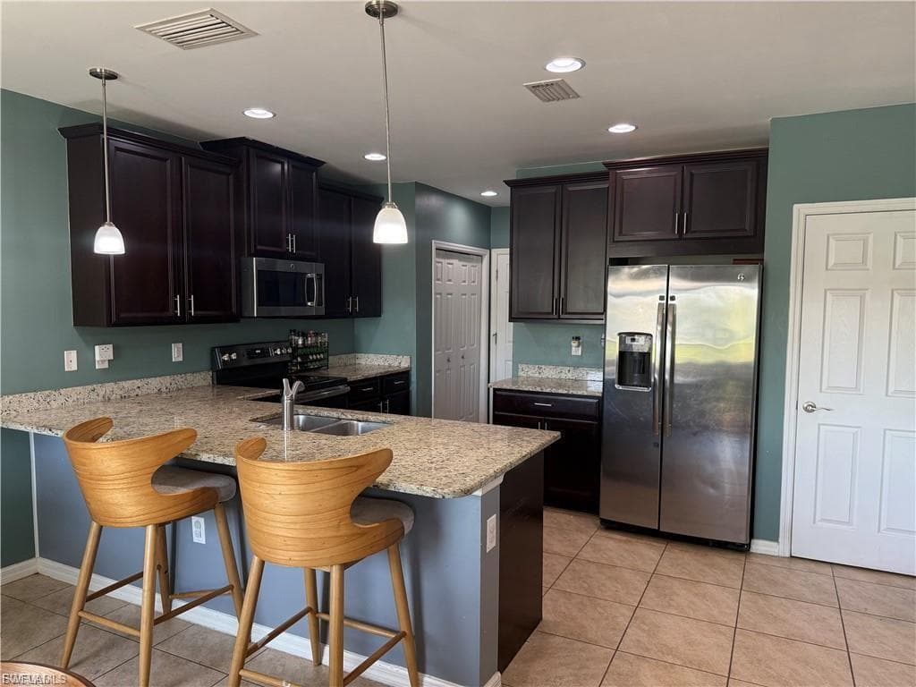 Kitchen featuring dark wood cabinetry, light-toned granite countertops, and stainless steel appliances