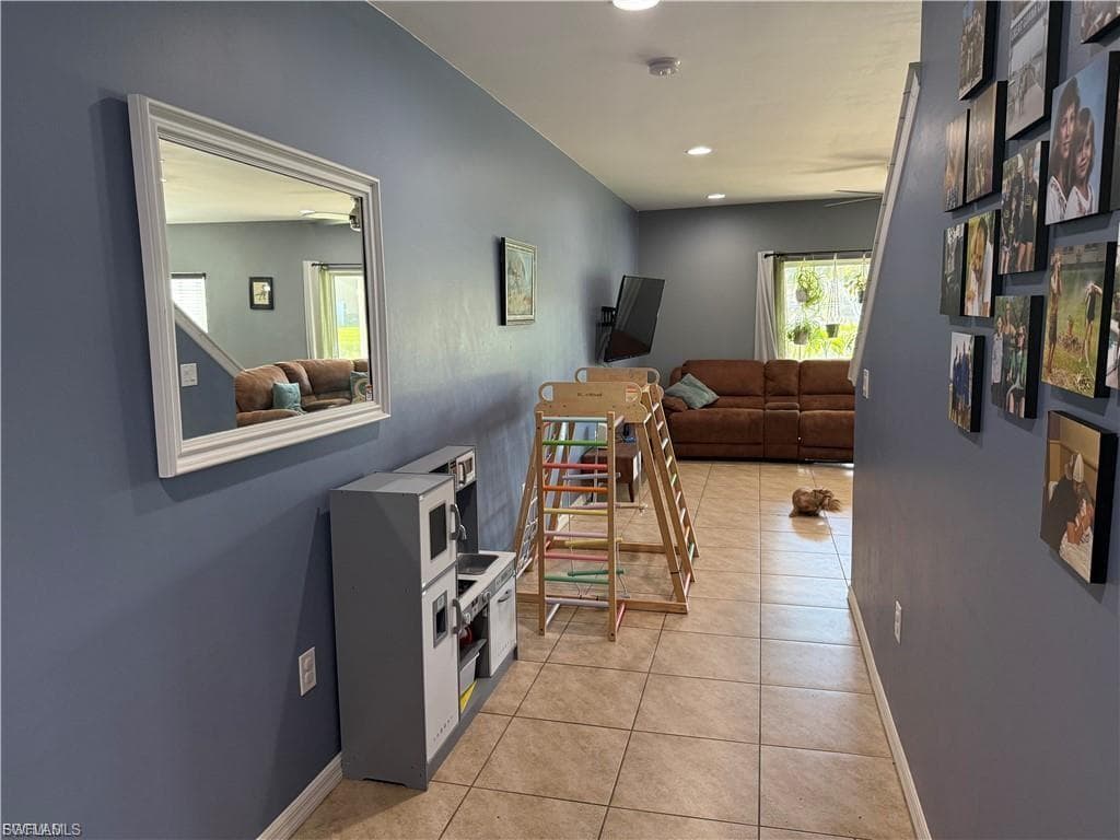 Hallway featuring neutral-toned tile flooring, recessed lighting, and a white framed mirror