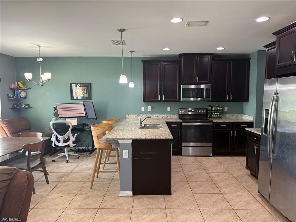 Kitchen featuring dark wood cabinetry, stainless steel appliances, granite countertops, and a central island with a breakfast bar