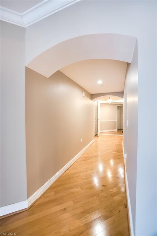 Hallway with hardwood / wood-style flooring and crown molding