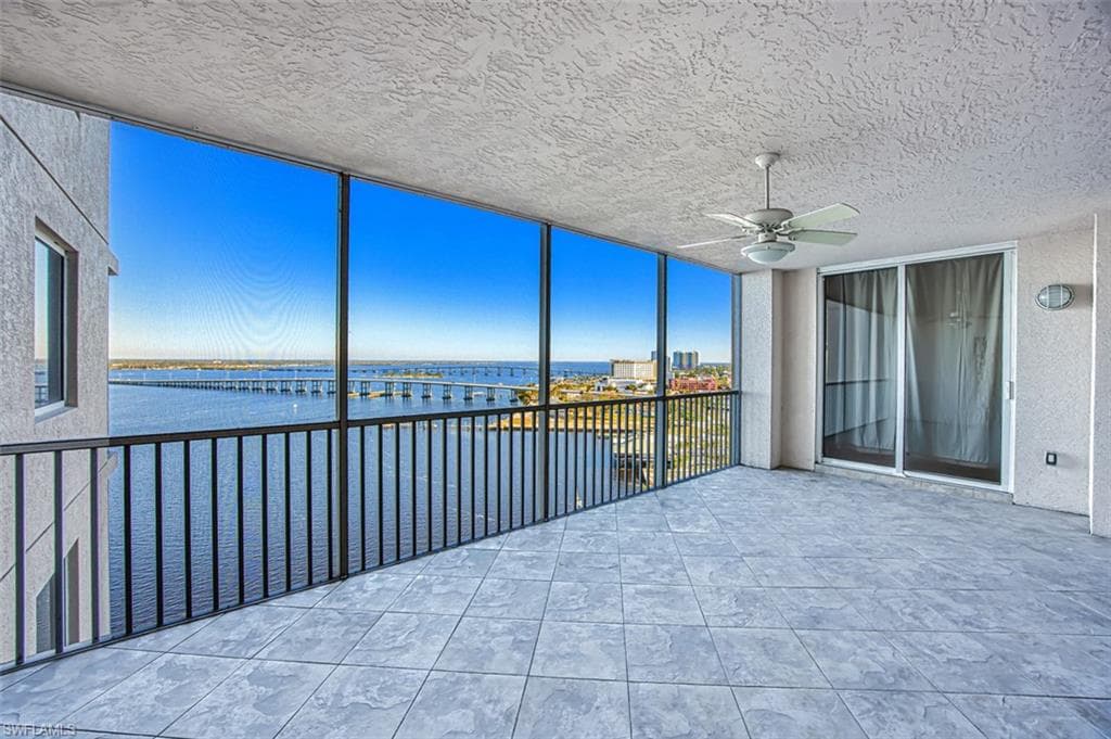 Unfurnished sunroom featuring ceiling fan and a water view