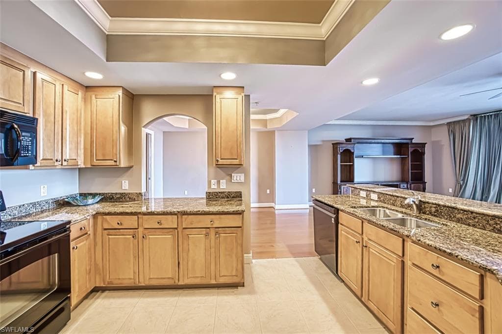 Kitchen with black appliances, ornamental molding, sink, and a tray ceiling