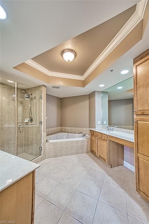 Bathroom with a tray ceiling, separate shower and tub, tile patterned flooring, and vanity