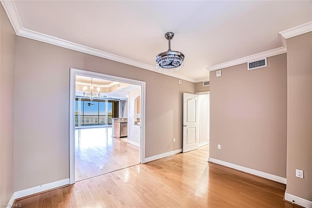 Unfurnished dining area featuring light wood-type flooring, ornamental molding, and a chandelier
