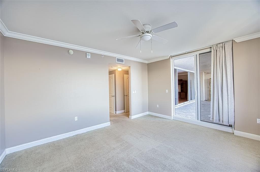 Carpeted empty room with ceiling fan and crown molding