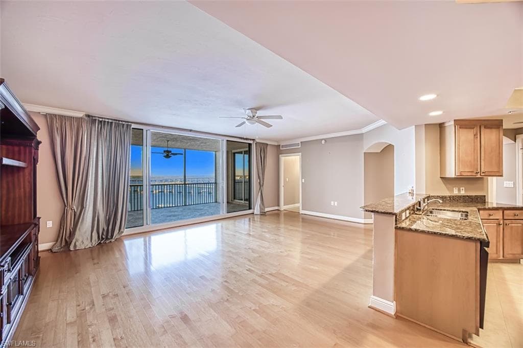Unfurnished living room featuring ceiling fan, light hardwood / wood-style floors, crown molding, and sink
