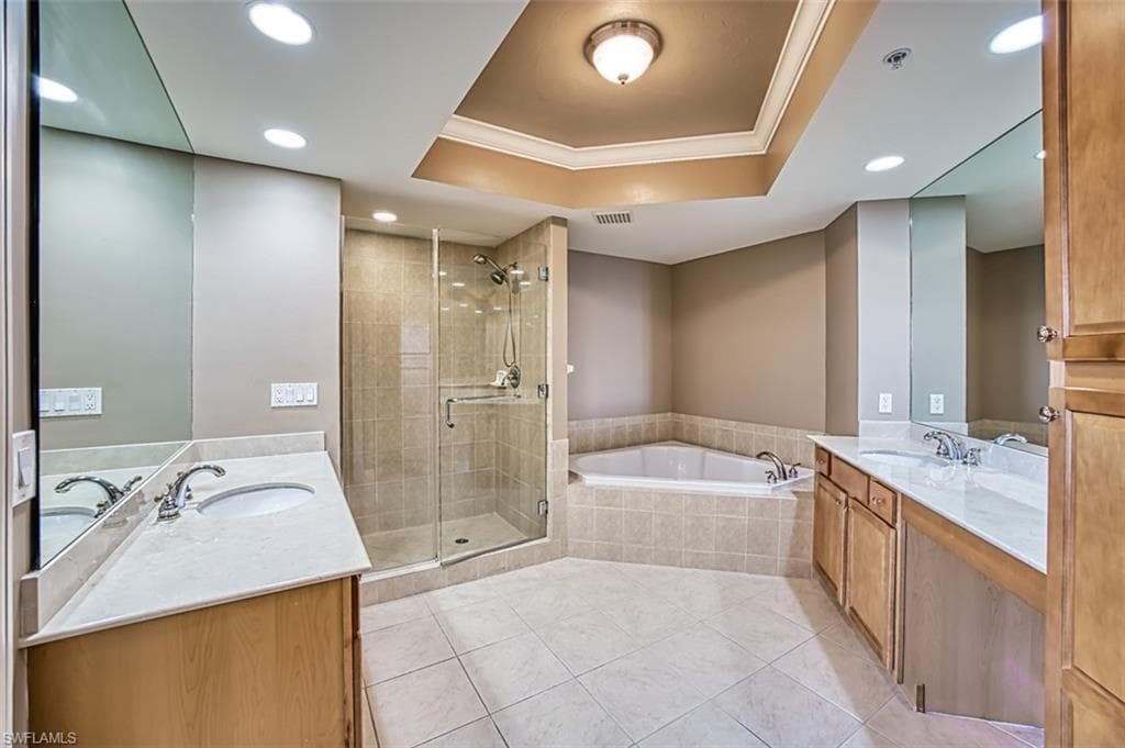 Bathroom featuring vanity, a raised ceiling, tile patterned flooring, ornamental molding, and shower with separate bathtub