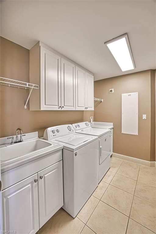 Laundry area with cabinets, sink, separate washer and dryer, and light tile patterned flooring