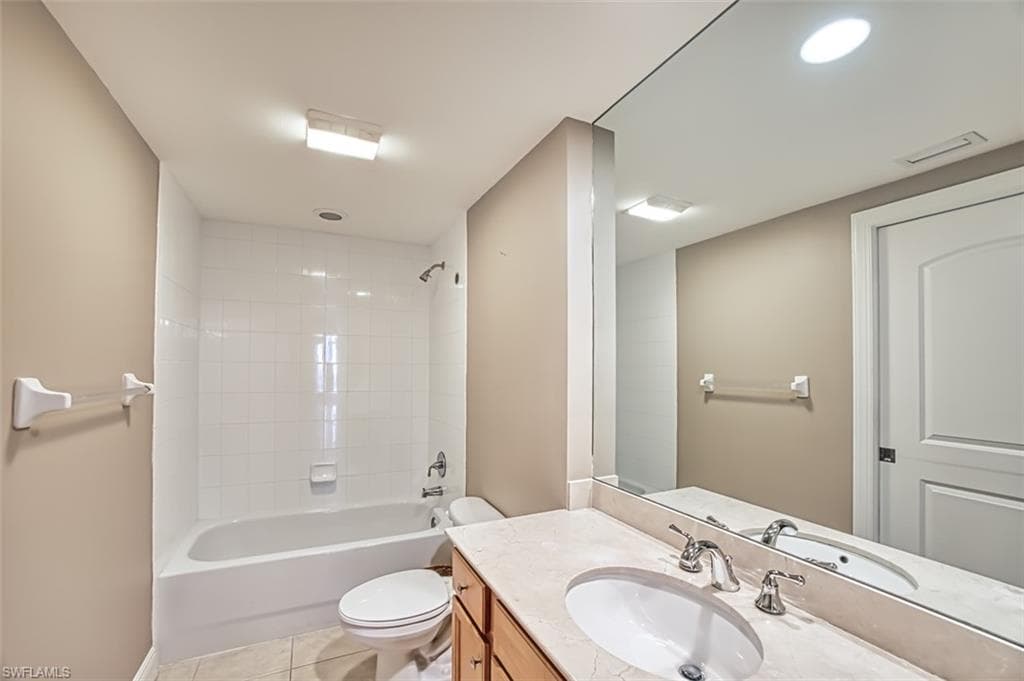 Full bathroom with toilet, vanity, tile patterned floors, and tiled shower / bath