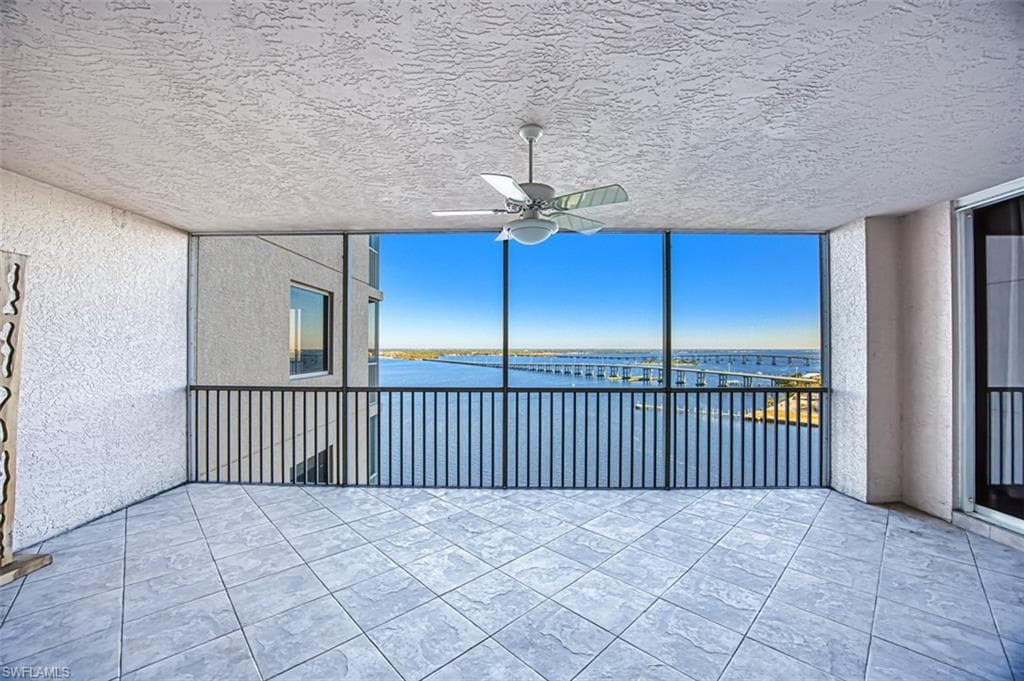 Unfurnished sunroom featuring a water view and ceiling fan