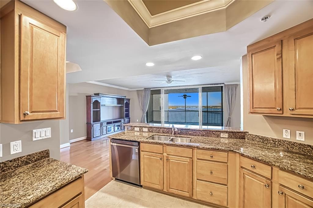 Kitchen featuring dishwasher, ornamental molding, sink, and dark stone counters