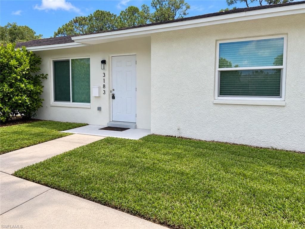 Stucco exterior with a white entry door and a covered entry