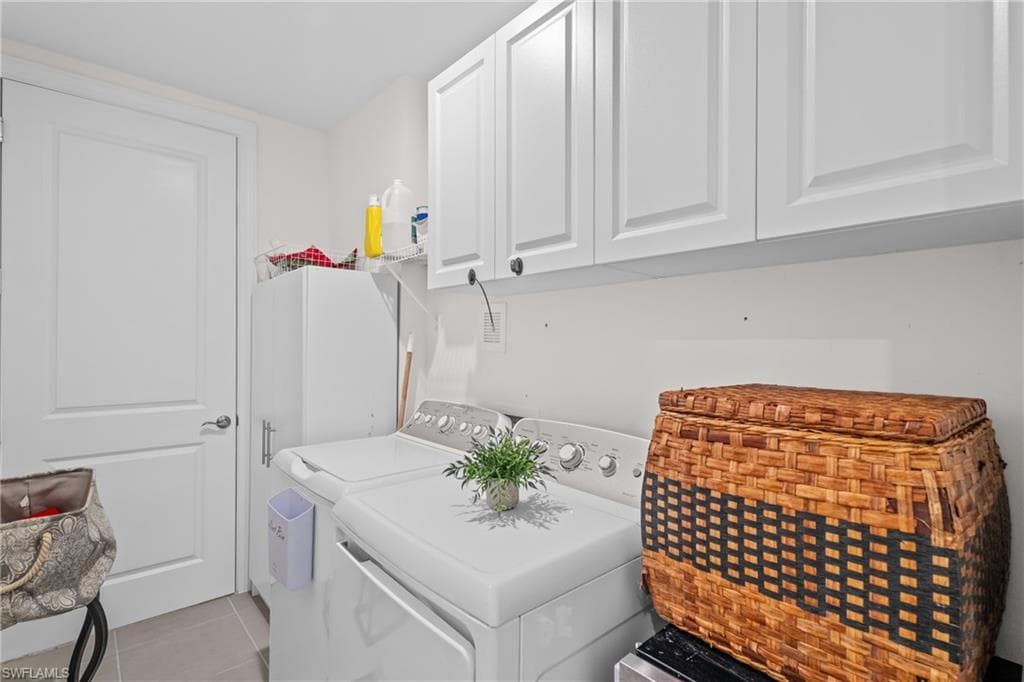 Washroom featuring light tile patterned floors, washer and dryer, and cabinet space