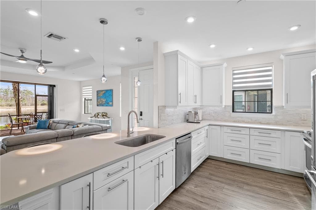 Kitchen featuring decorative light fixtures, open floor plan, white cabinets, recessed lighting, and light stone countertops