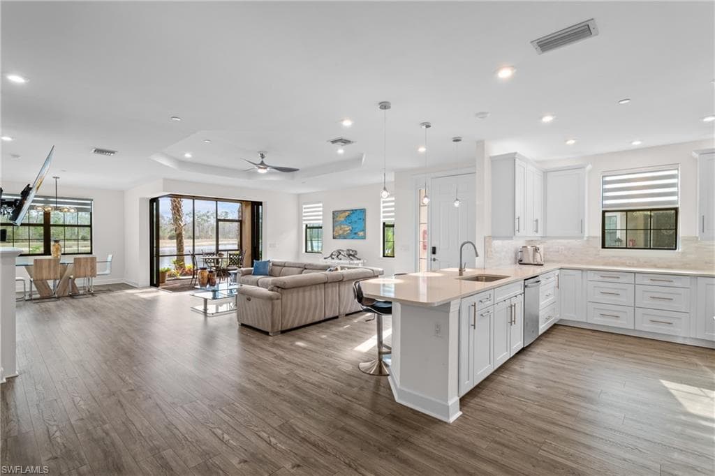 Kitchen featuring hanging light fixtures, a kitchen breakfast bar, white cabinets, open floor plan, and dark wood-style flooring