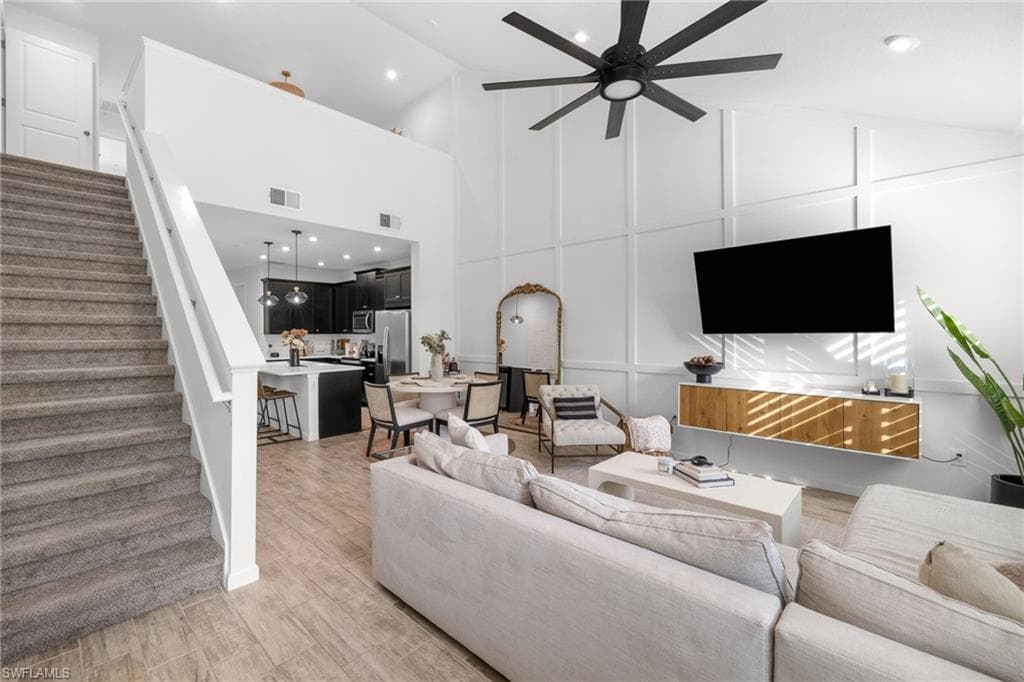 Open-concept living area featuring high vaulted ceilings, a modern ceiling fan, and board and batten accent wall
