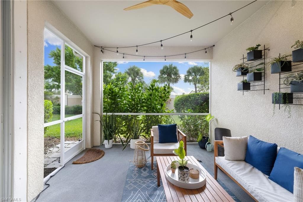 Enclosed screened patio featuring a ceiling fan, string lighting, and ample natural light