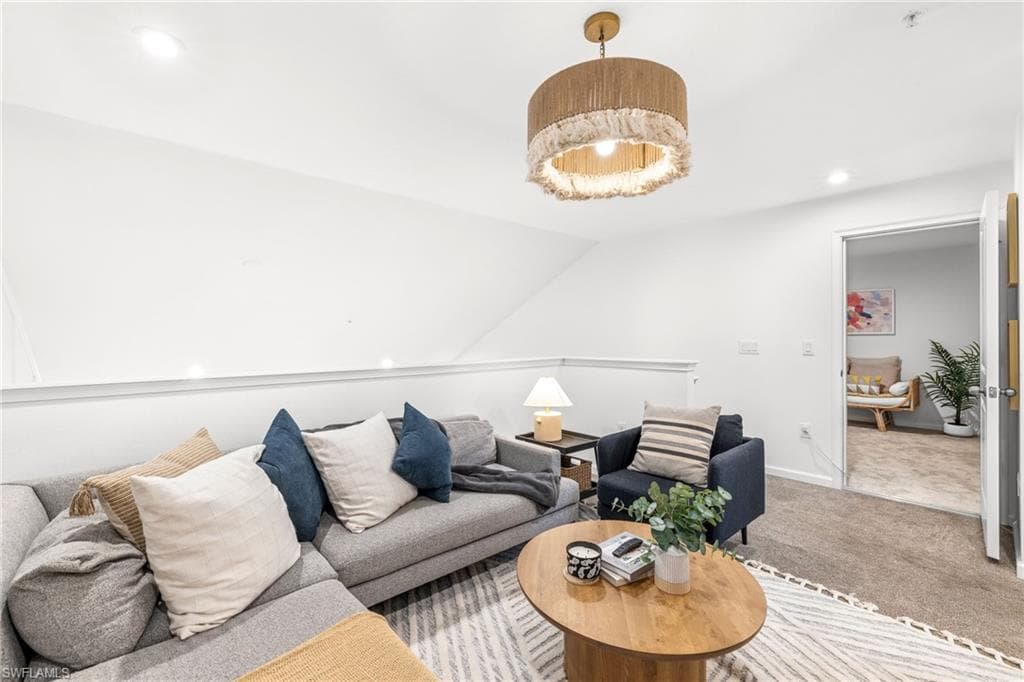 Carpeted loft area featuring a decorative drum pendant light fixture, a half-wall railing, and recessed ceiling lighting