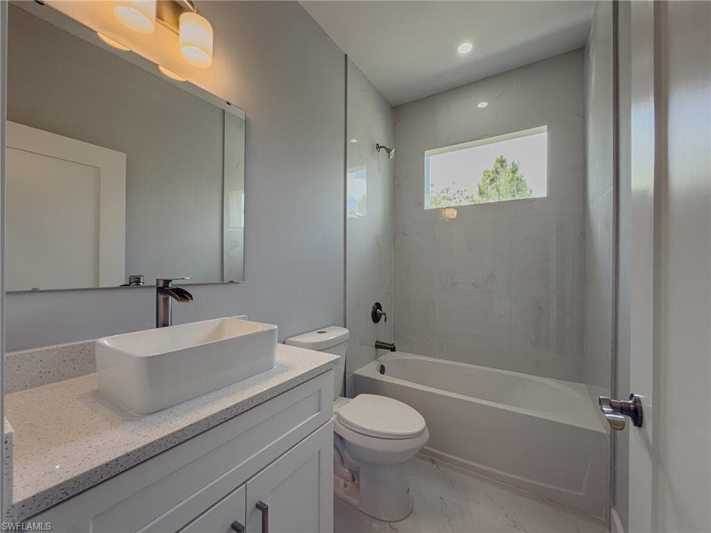 Bathroom featuring vanity, toilet, shower combination, and marble finish floor