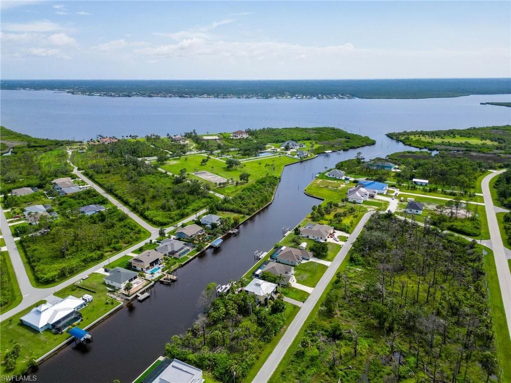 Aerial view of property and surrounding area featuring a nearby body of water and nearby suburban area