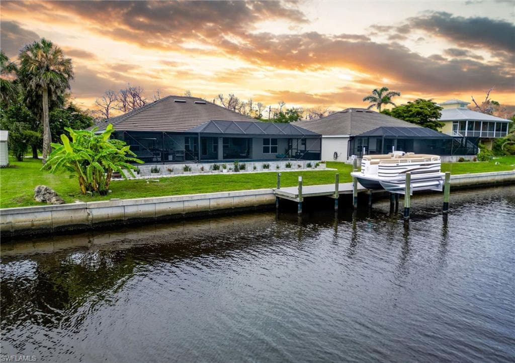 Dock with a water view, a lanai, and a lawn