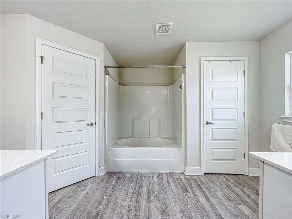 Full bathroom with vanity, wood finished floors, and tub / shower combination