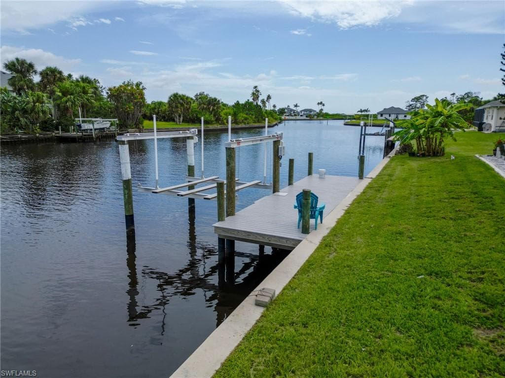 Dock area featuring boat lift, a yard, and a water view